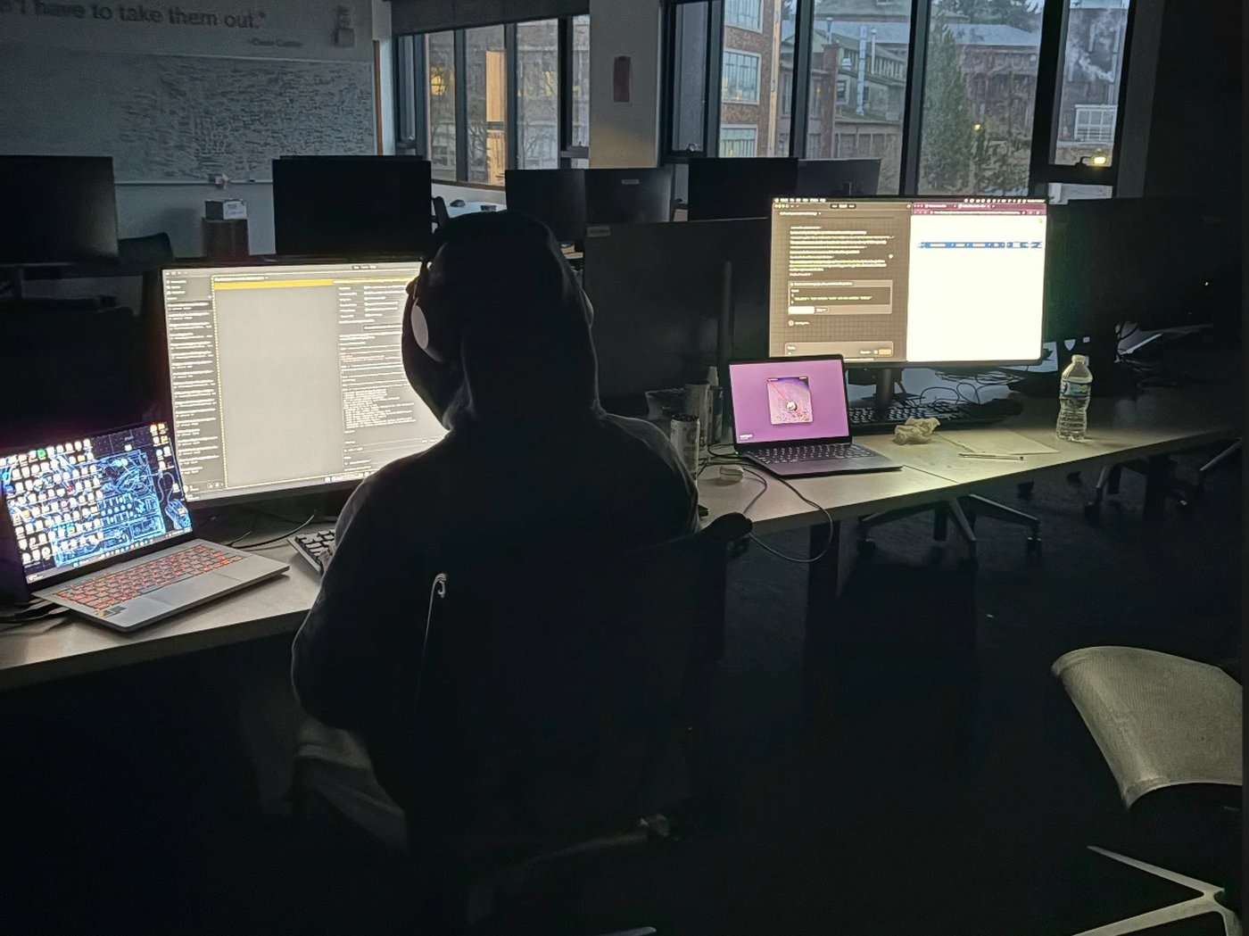 A dark computer lab, monitors lit, working late